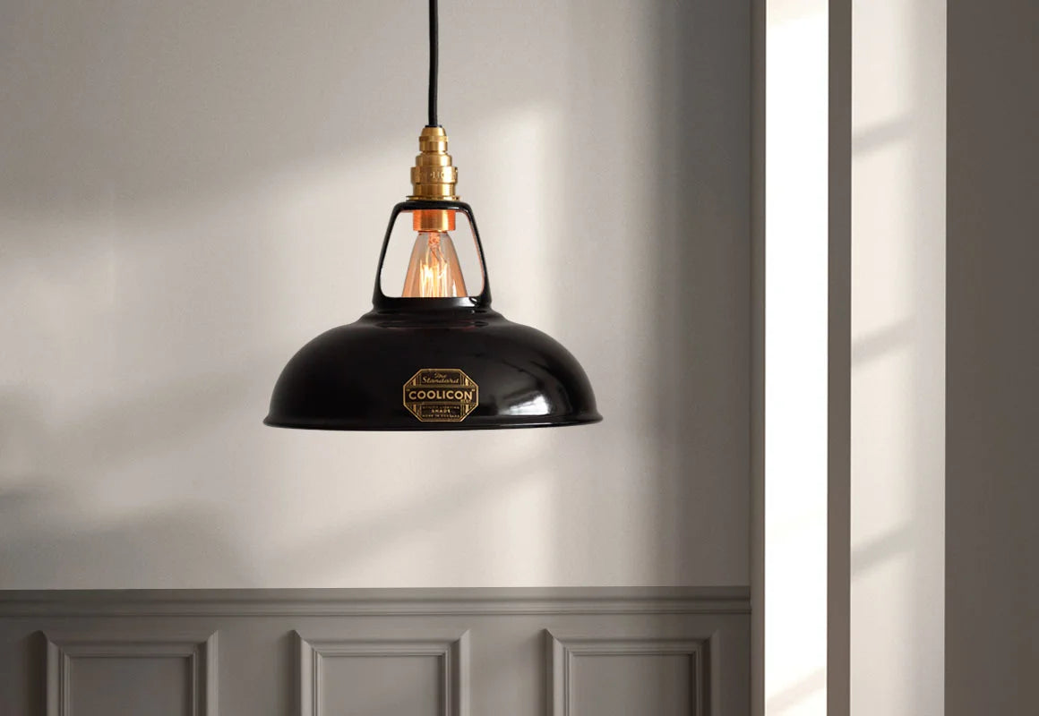 An Original Jet Black shade hanging against a grey wall with brown moulding near a window