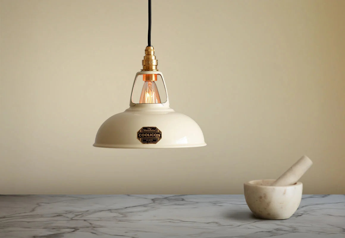 A Coolicon Classic Cream lampshade hanging over a marble table. A marble mortar and pestle are placed on the table