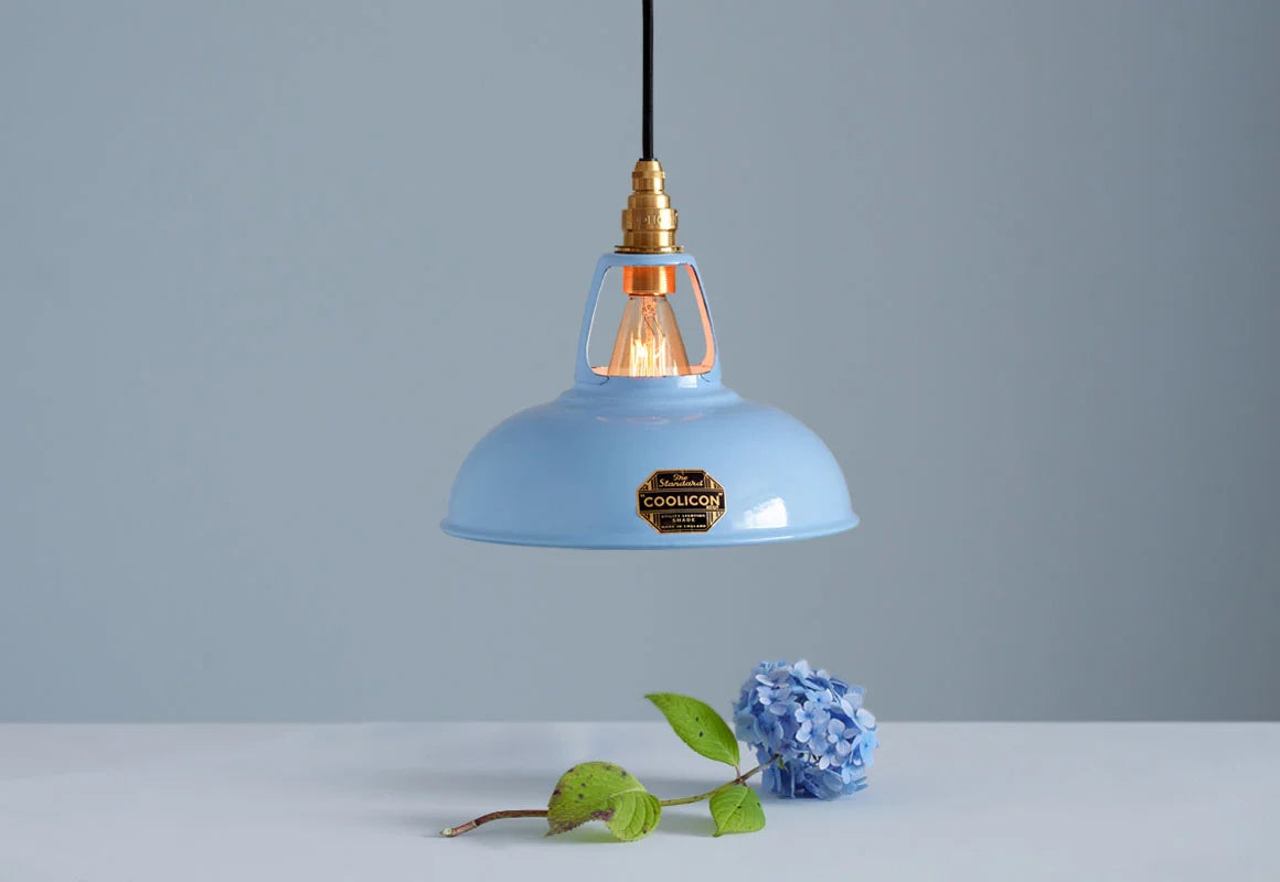 A Coolicon Sky Blue lampshade with a Brass pendant set hanging above a blue hydrangea flower