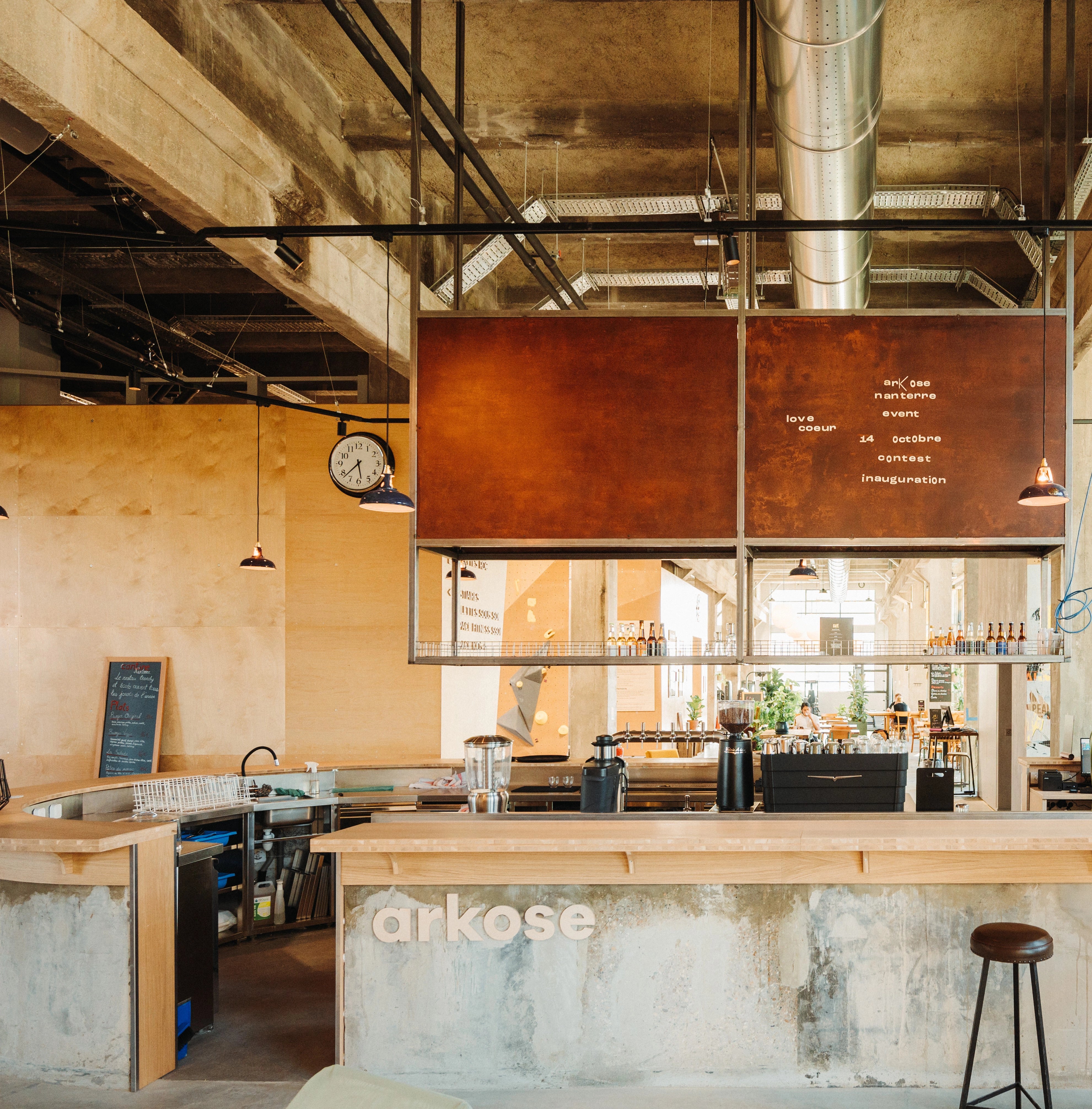 Bespoke purple Coolicon 1933™ lampshades suspended above the Arkose reception, providing warm industrial lighting in a high‑ceiling commercial space.