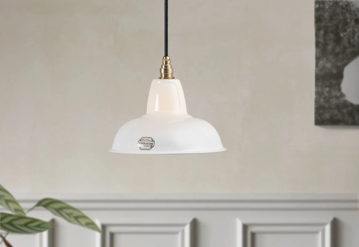 A Fine Bone China Silhouette Coolicon shade with a Signature Brass pendant set hangs over a light cream wall with grey moulding