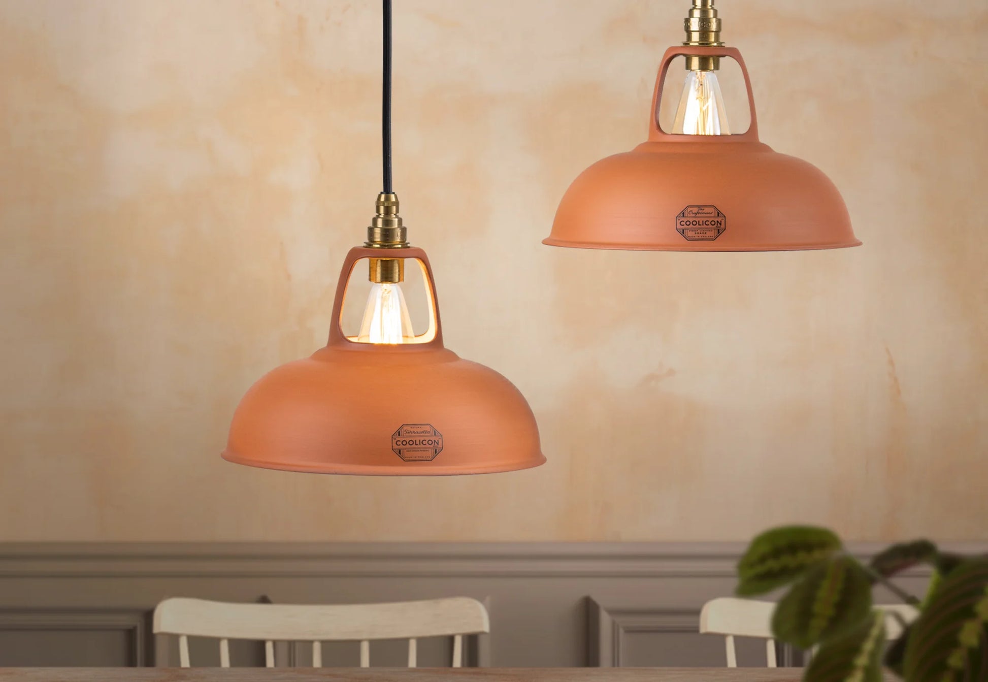 Two Natural Terracotta shades hanging above a table with a textured wall in the background