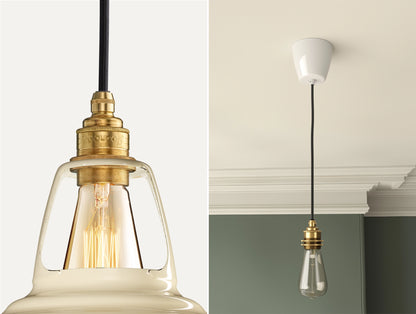 Close up of an E27 Signature Brass suspension set on a Paper Cream lampshade on the left. On the right, an E27 Brass pendant set with a lightbulb is hanging from the ceiling