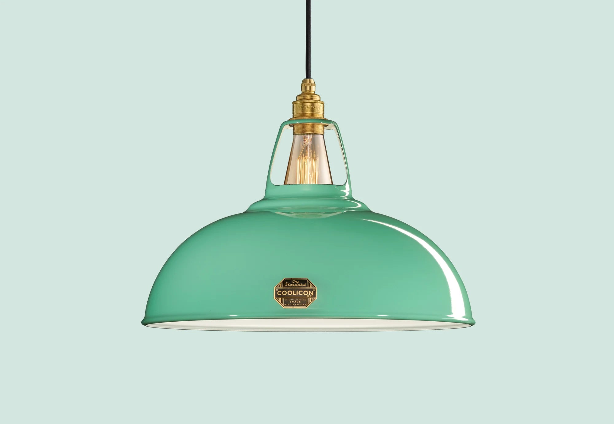 A Large Teal Enamel pendant lampshade hanging in front of a neutral green background.