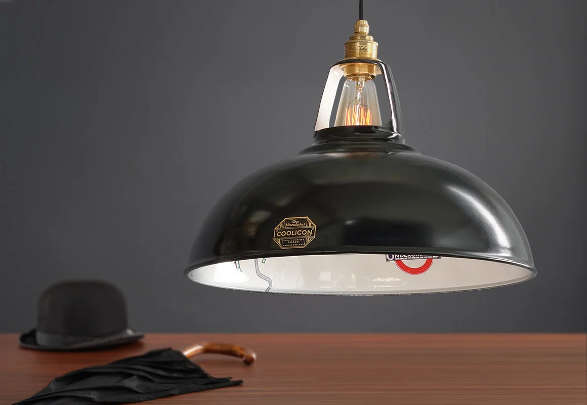 A Large Northern Line shade above a wooden table. Below it is a black bowler hat and a black umbrella.