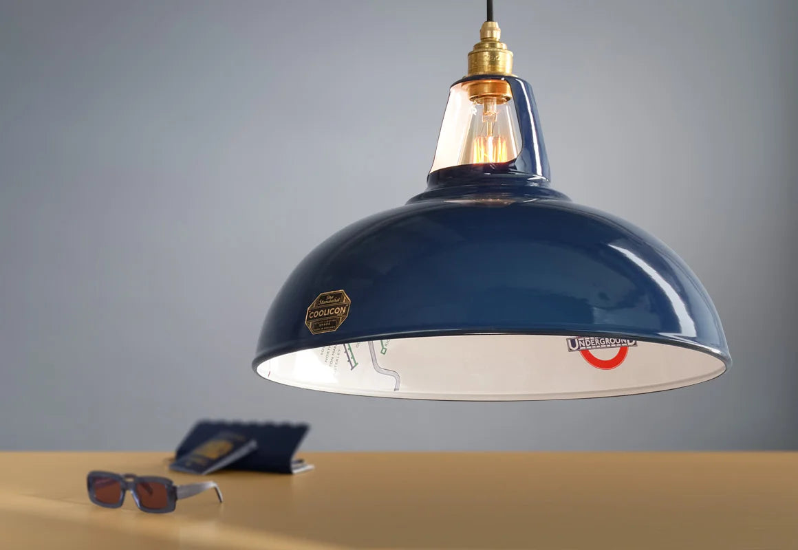 A Large Piccadilly Line Blue shade above a table. Below it is a blue purse, a blue British passport and a pair of blue sunglasses