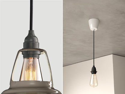 Close up of an E27 Industrial suspension set on an Original Grey lampshade on the left. On the right, an E27 Industrial pendant set with a lightbulb is hanging from the ceiling