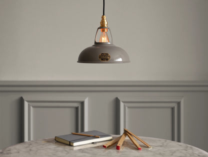 A Coolicon Original Grey lampshade hanging over a marble table. Below there are a grey notebook, an orange pencil and a wooden folding ruler 