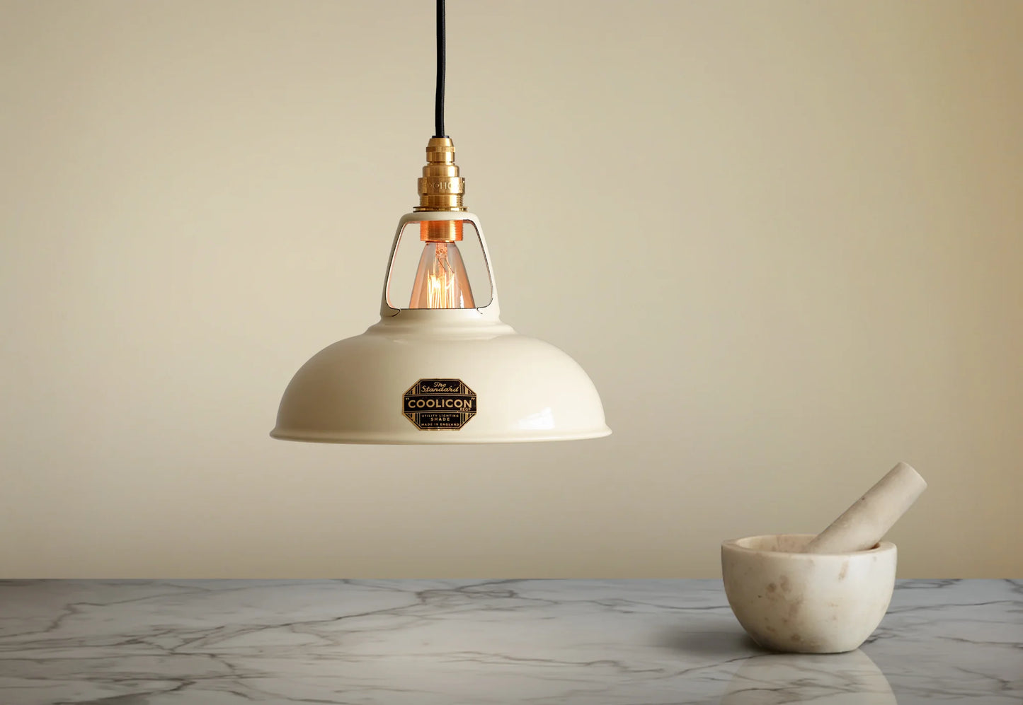 A Coolicon Classic Cream lampshade hanging over a marble table. A marble mortar and pestle are placed on the table