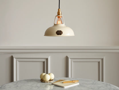 A Coolicon Classic Cream lampshade hanging over a marble table. Three cream snooker balls, two notebooks and an orange pen are placed on the table