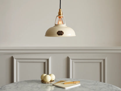 A Coolicon Classic Cream lampshade hanging over a marble table. Three cream snooker balls, two notebooks and an orange pen are placed on the table