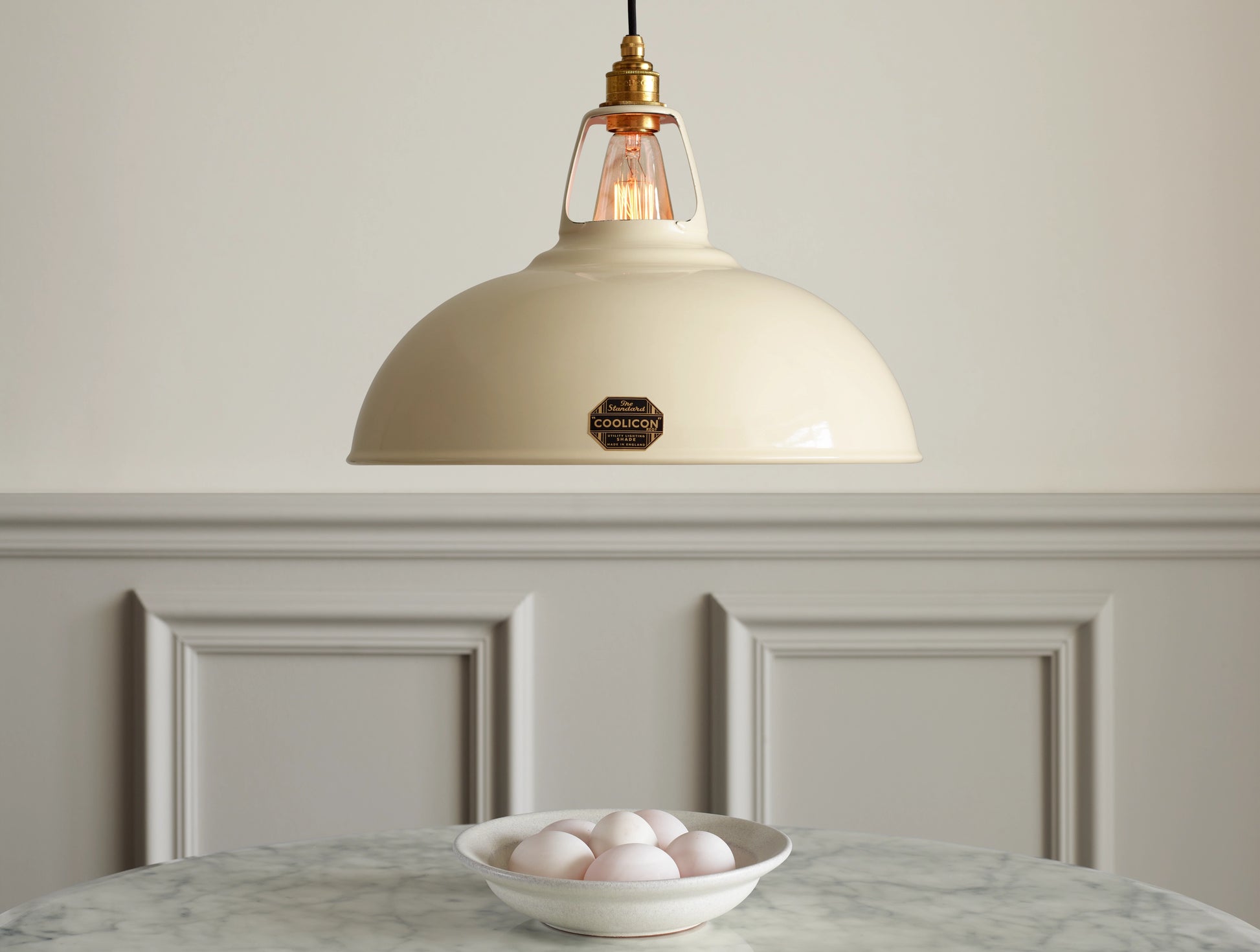 A Large Coolicon Classic Cream lampshade hanging over a marble table. A bowl with duck eggs is placed on a marble table under the shade