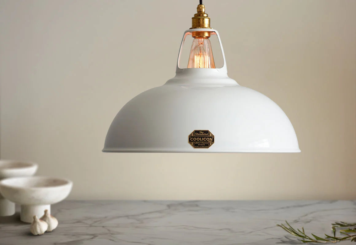 A Large Coolicon Original White lampshade hanging over a marble table. Below the shade is a marble salad bowl, a garlic bulb and a tree branch