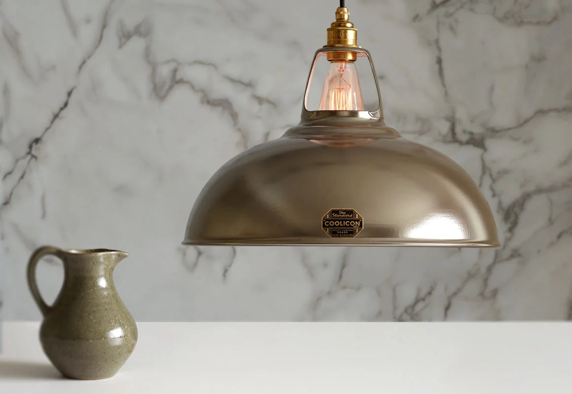 A large Antinium shade hanging over a table above a grey water jug and a golden spoon and fork. The background is a marble wallpaper