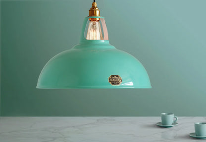 A Coolicon Fresh Teal lampshade hanging over a table. Below the shade are two teal espresso cups and saucers.