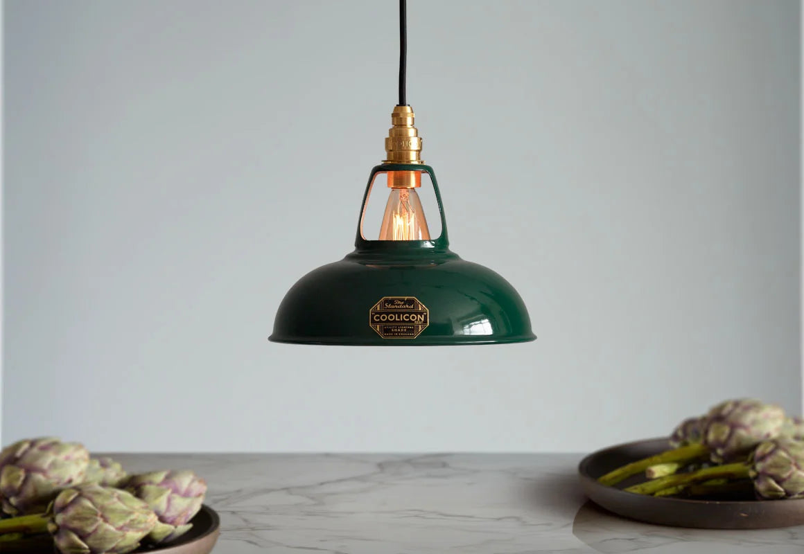 A Coolicon Original Green lampshade hanging over a marble table with bowls of artichokes.