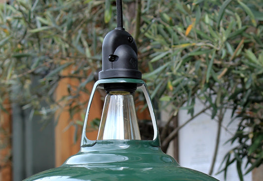 Green Coolicon Pendant lampshade with an IP65 water-resistant fitting and black over braided fabric cable in front of green olive garden tree