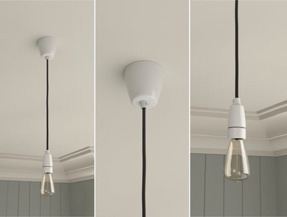 An E14 Porcelain Coolicon pendant set with a Vitreous Enamel ceiling cup and an E14 lightbulb hanging from a ceiling in front of a Georgian-style wall