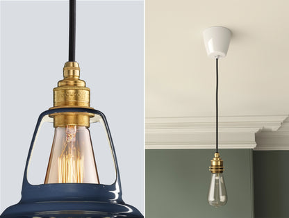 Close up of an E27 Signature Brass suspension set on a Selvedge lampshade on the left. On the right, an E27 Brass pendant set with a lightbulb is hanging from the ceiling