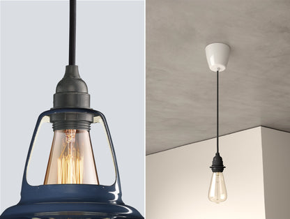 Close up of an E27 Industrial suspension set on a Selvedge lampshade on the left. On the right, an E27 Industrial pendant set with a lightbulb is hanging from the ceiling