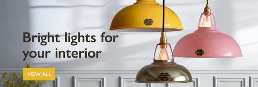 Three lampshades hanging in front of a grey wall. The text on the image is “bright lights for your interior”.