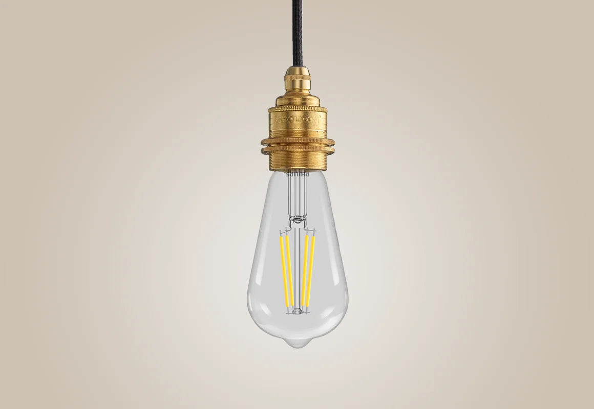 E27 LED Lightbulb hanging over a light background. The lightbulb is fitted with a Coolicon Brass Suspension Set