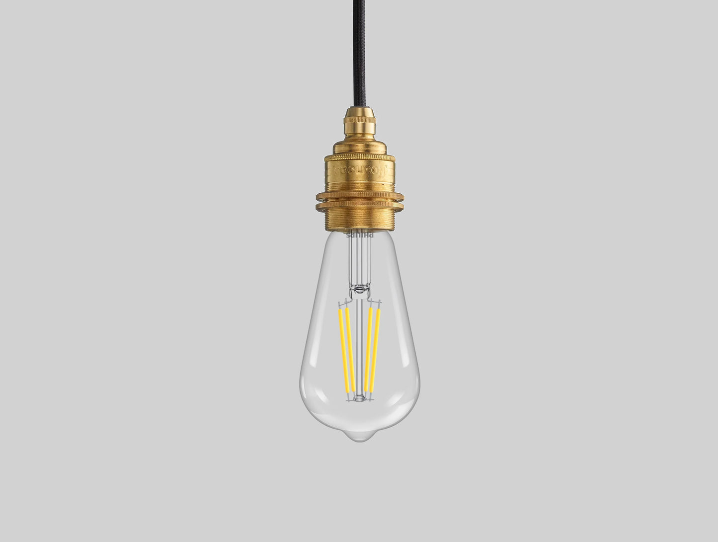 E27 LED Lightbulb hanging over a grey background. The lightbulb is fitted with a Coolicon Brass Suspension Set