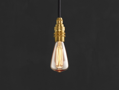 E14 decorative Lightbulb hanging over a black background. The lightbulb is fitted with a Coolicon Brass Suspension Set