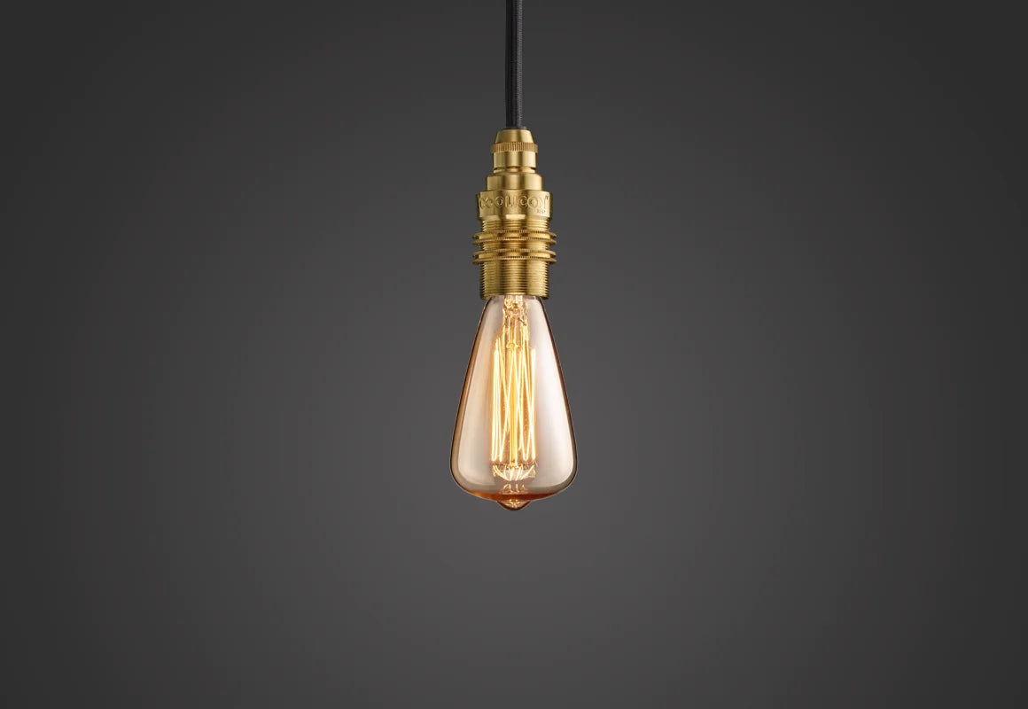 E14 decorative Lightbulb hanging over a black background. The lightbulb is fitted with a Coolicon Brass Suspension Set