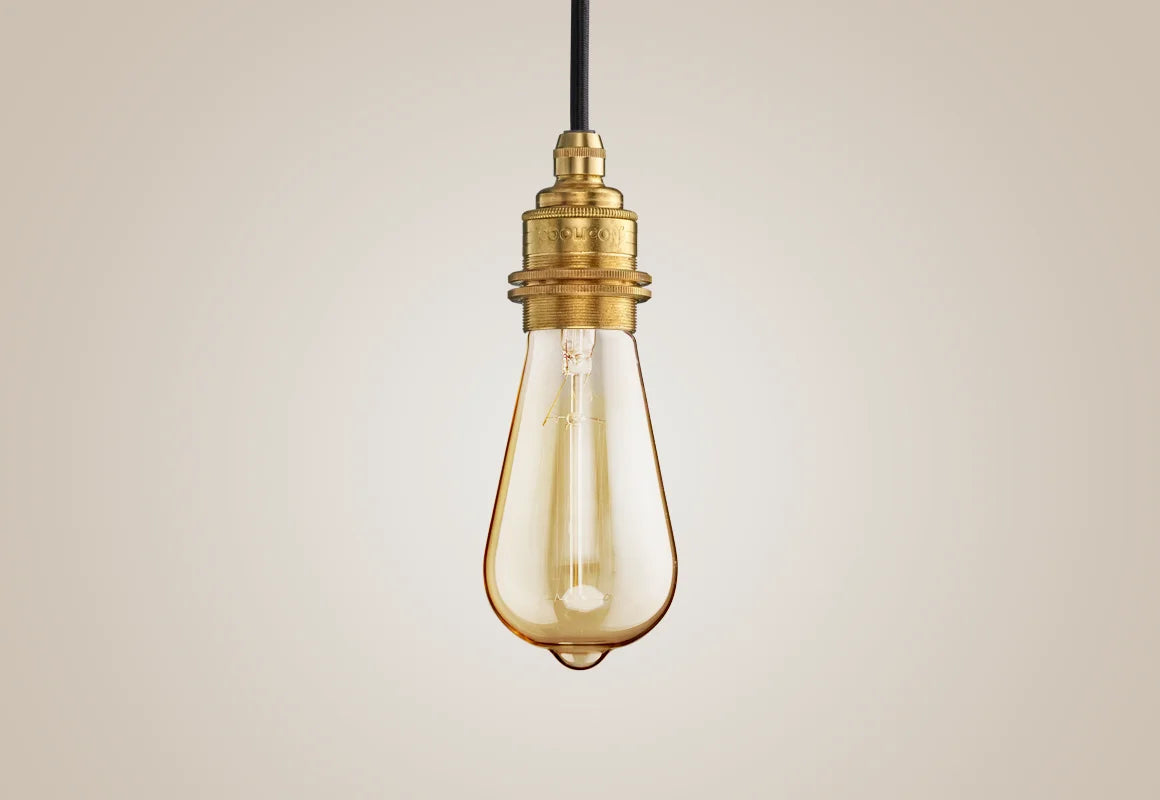 E27 decorative Lightbulb hanging over a light background. The lightbulb is fitted with a Coolicon Brass Suspension Set