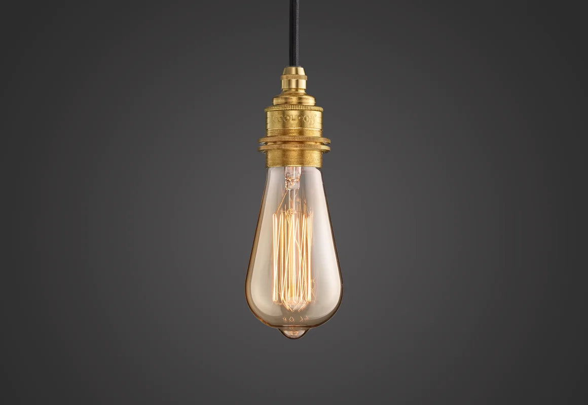 E27 decorative Lightbulb hanging over a black background. The lightbulb is fitted with a Coolicon Brass Suspension Set