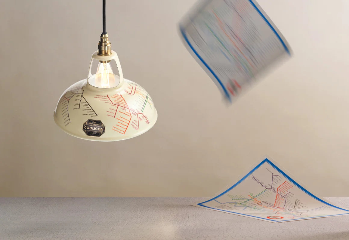 An Original Underground Map shade hanging over a table. In the background, two 1933 maps are falling from the ceiling