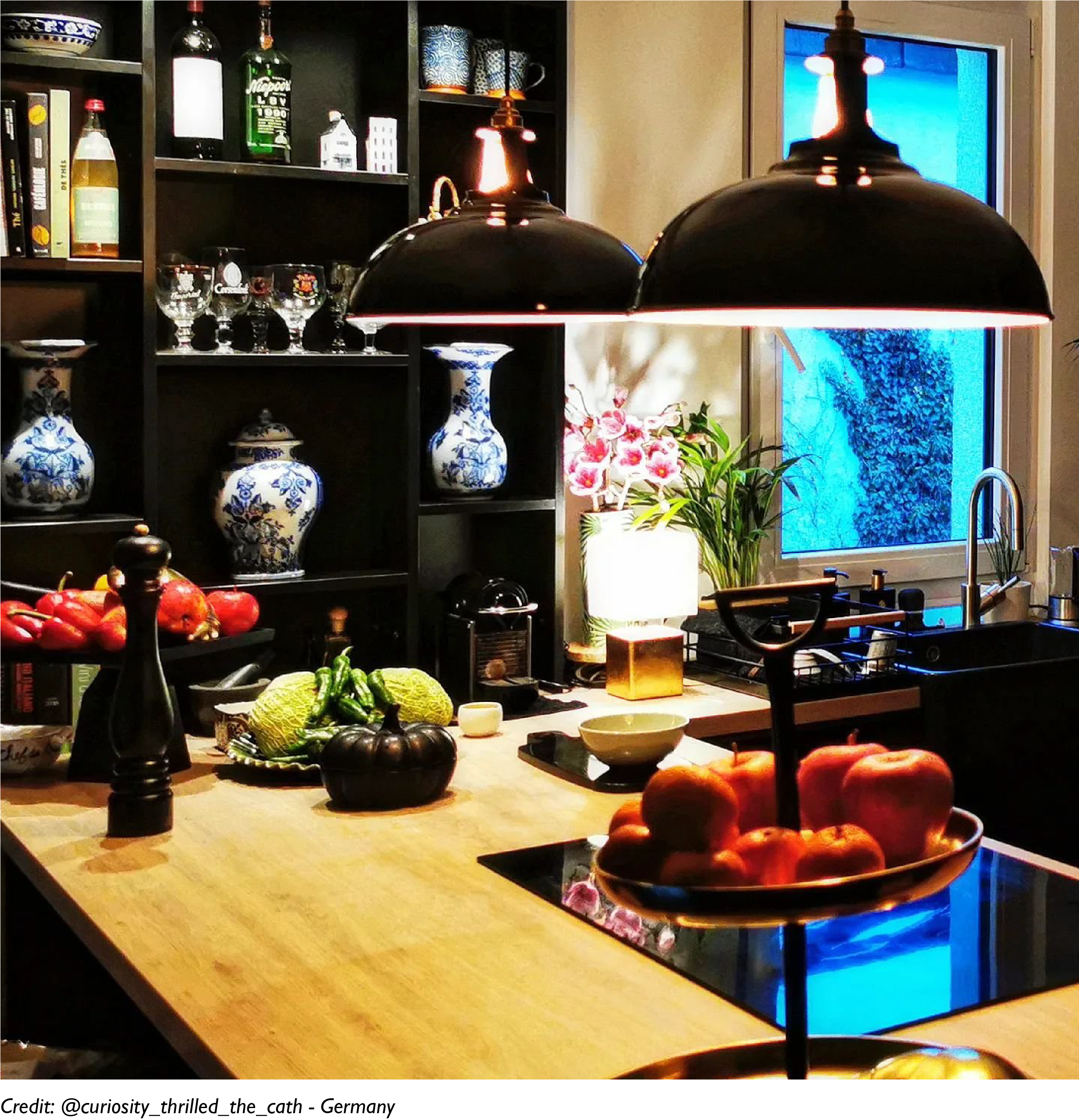 Two Large Jet Black lamps hang over a cooker and a kitchen island