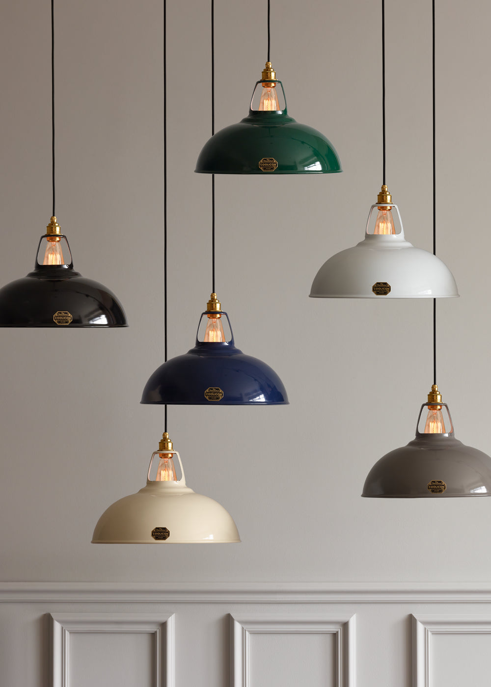 Six large Coolicon lampshades hanging, the colours of the shades are, from top to bottom: Jet Black, Original Green, Original White, Original Grey, Royal Blue and Classic Cream