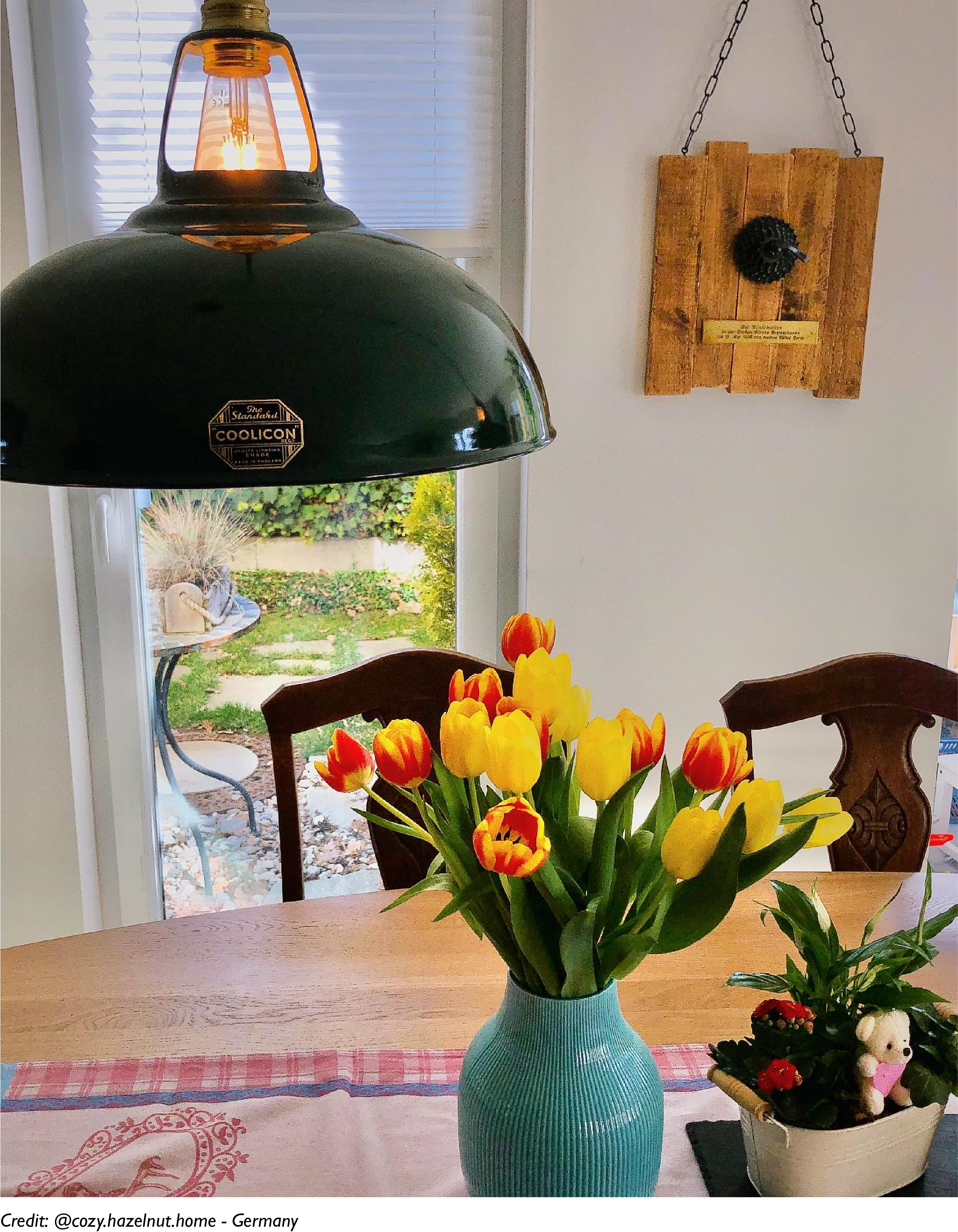 A Large Green shade hangs over a wooden dining table