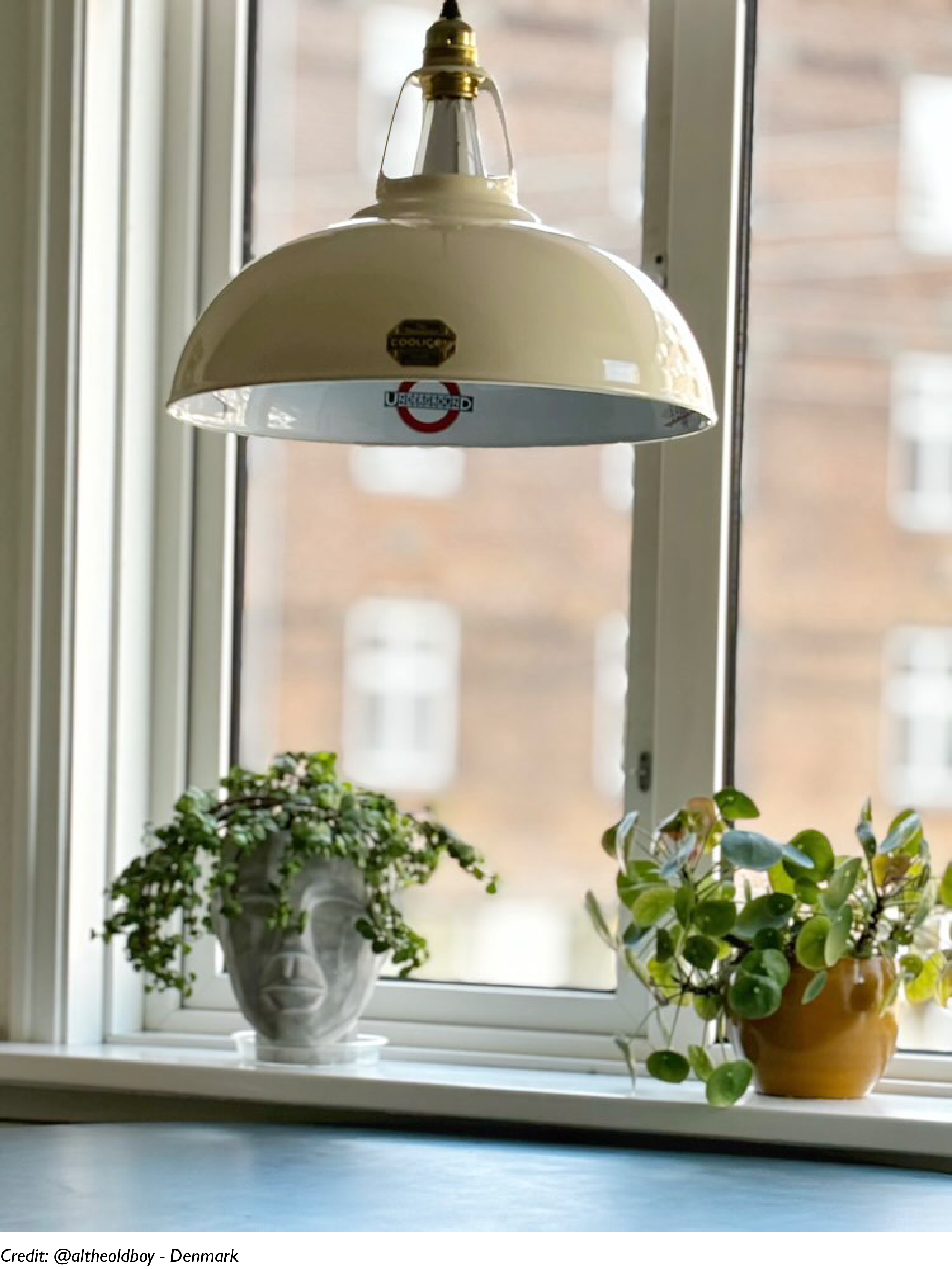 A Paper Cream lampshade hanging in front of a window, showing the London Underground logo