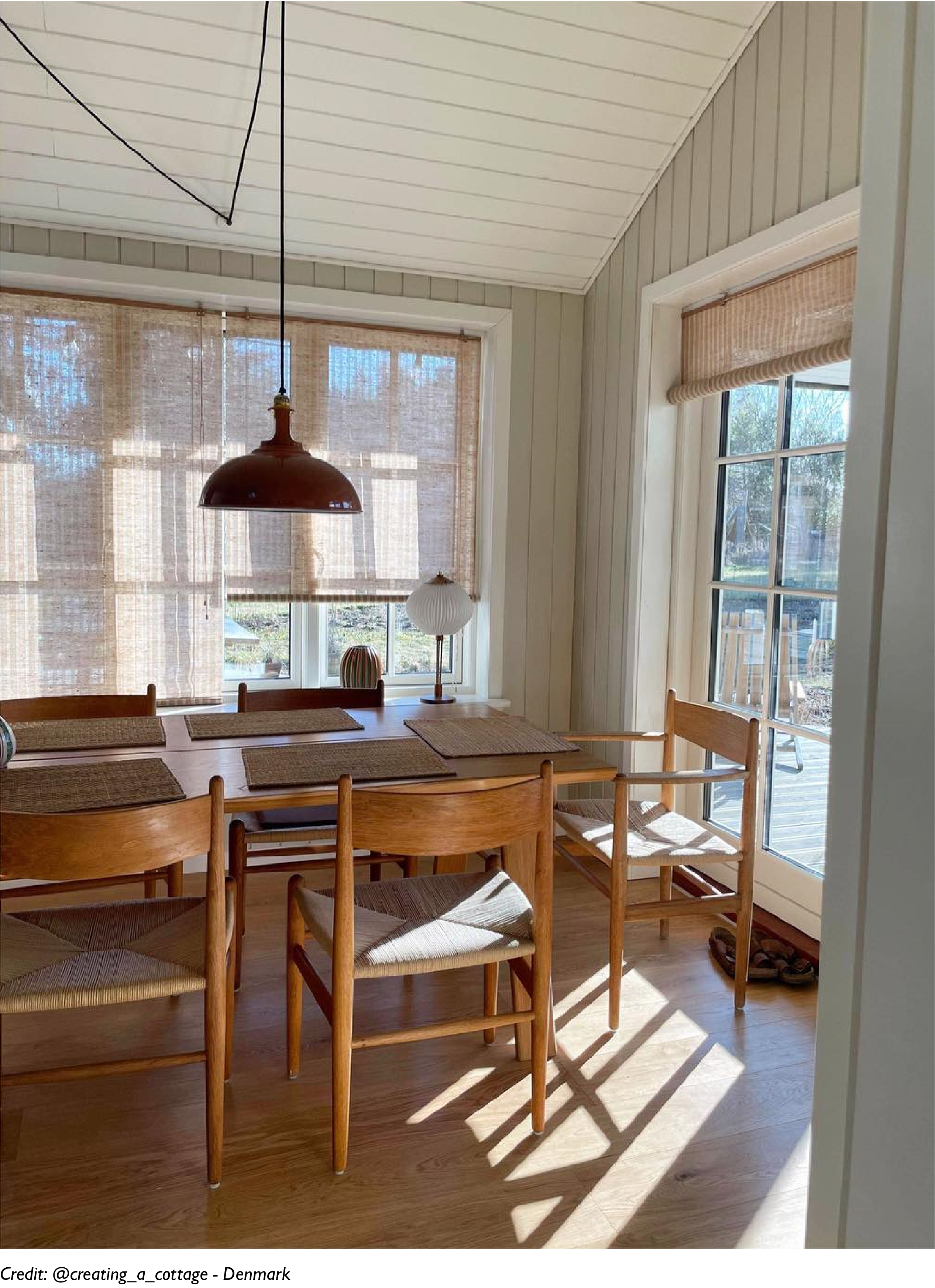 A Large Terracotta lamp hangs over a wooden table in a minimalist interior
