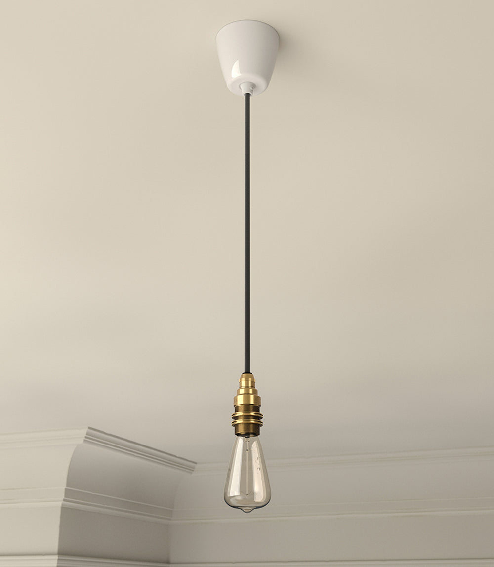 An E14 Signature Brass lampholder hanging from the ceiling, with a black cable and a Vitreous Enamel Ceiling cup