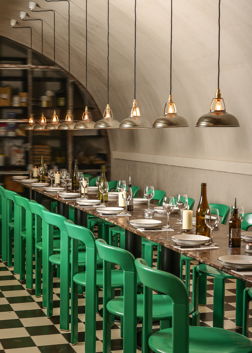 Original Antinium lampshades hanging over a dark table, with bright green chairs around