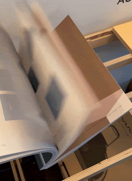 Three Coolicon product Catalogues stacked onto the middle shelf of a plywood Point of Sale Display Stand next to an Original Yellow Coolicon Lampshade.