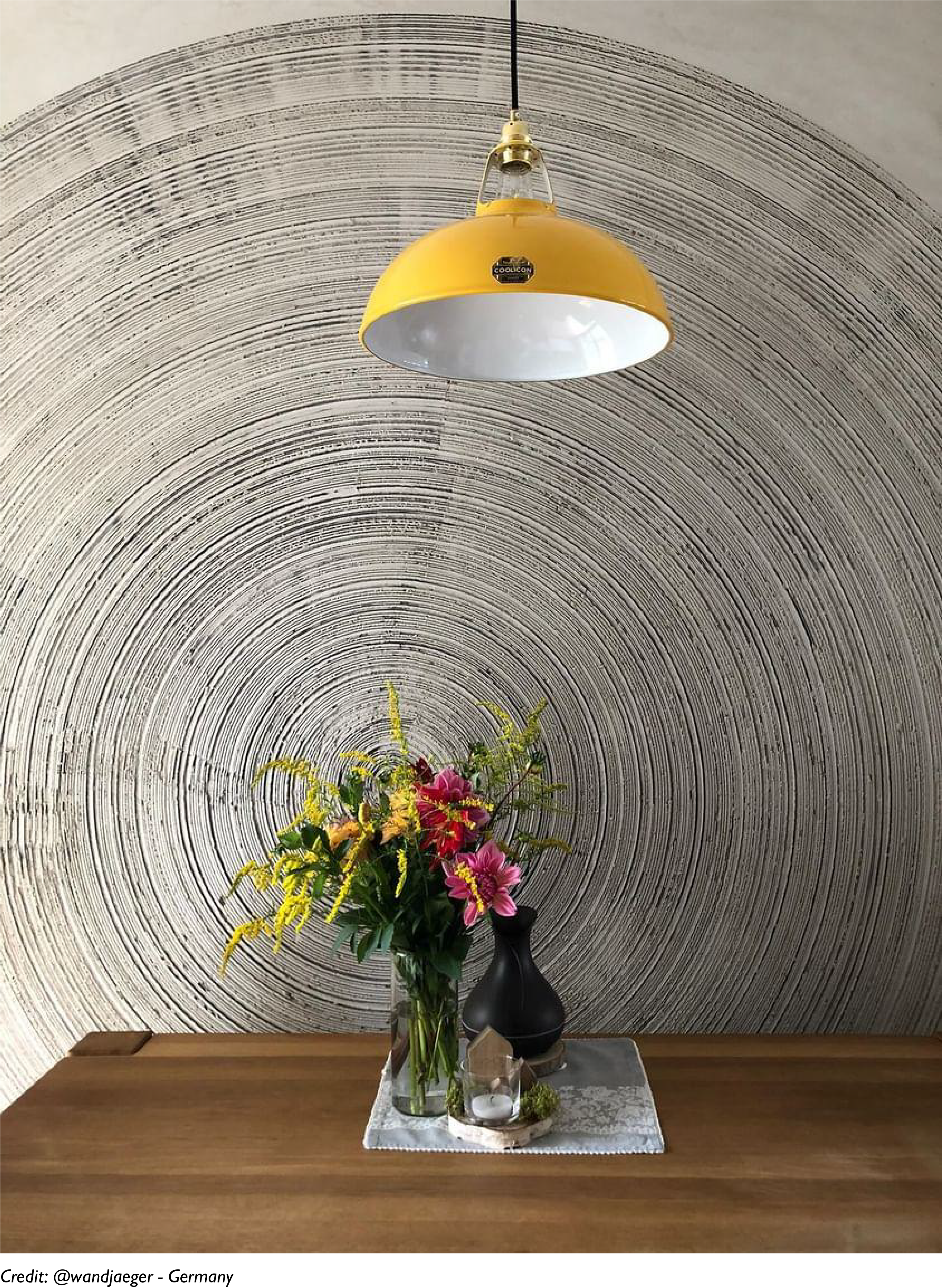 A Deep Yellow lampshade hangs over a dining table against a textured wall
