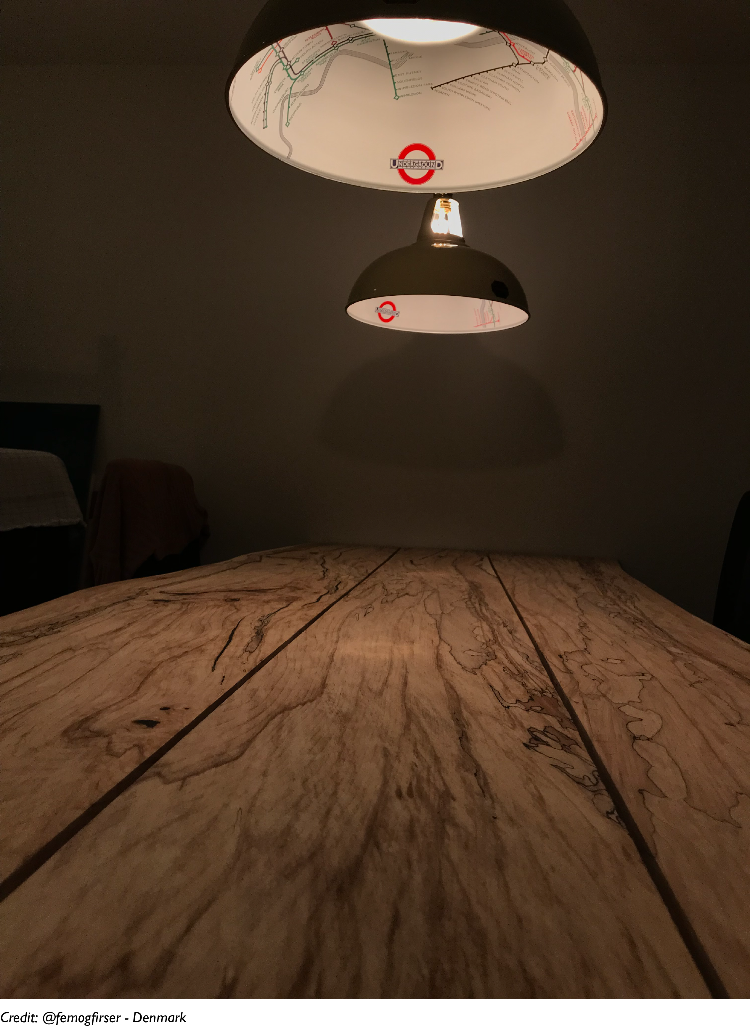 Two large London Underground lampshades lighting a wooded dining table