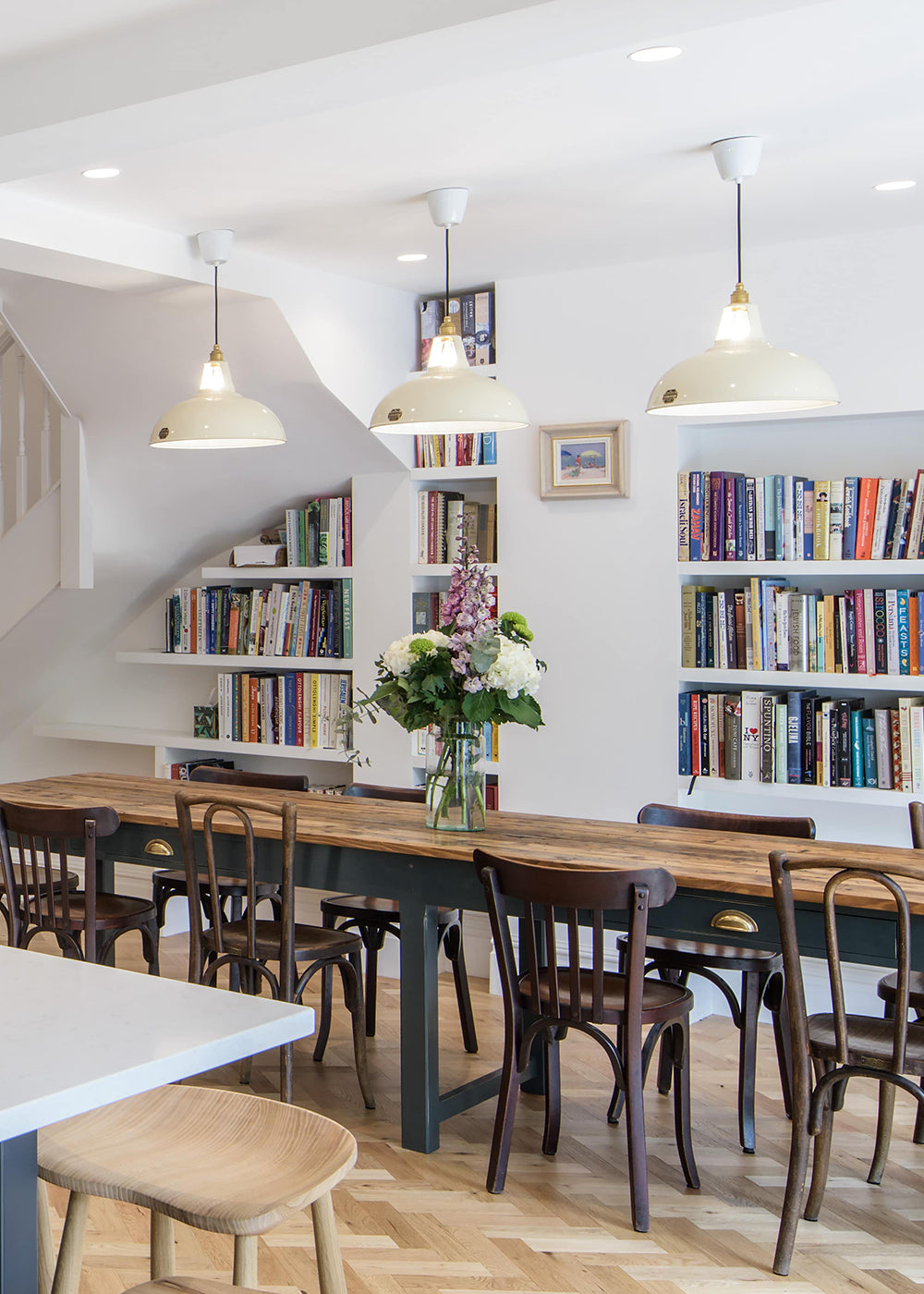 Three Large Classic Cream lamps hanging over a large dining table with ten chairs