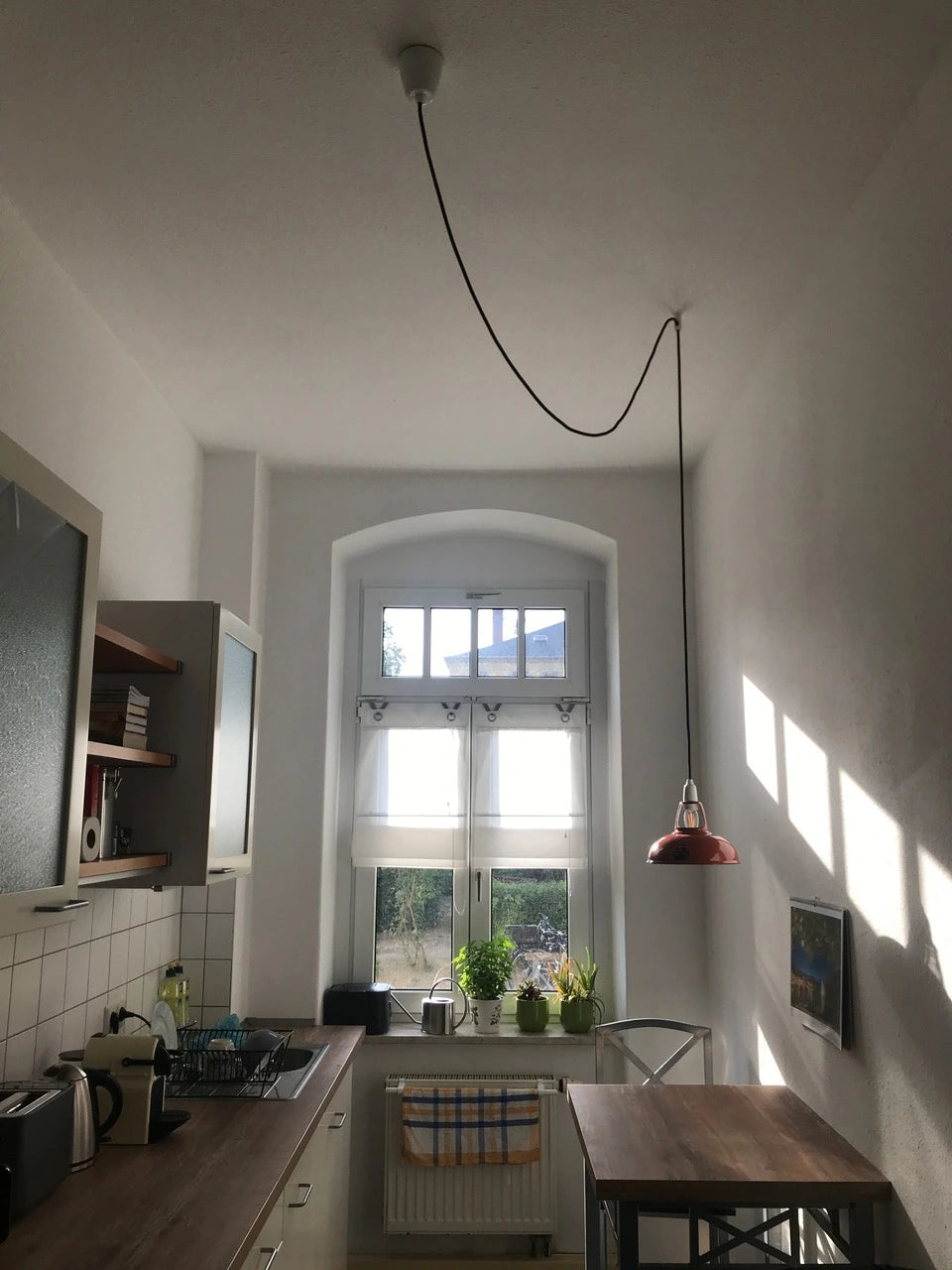 An Original Terracotta lampshade hangs over a kitchen table