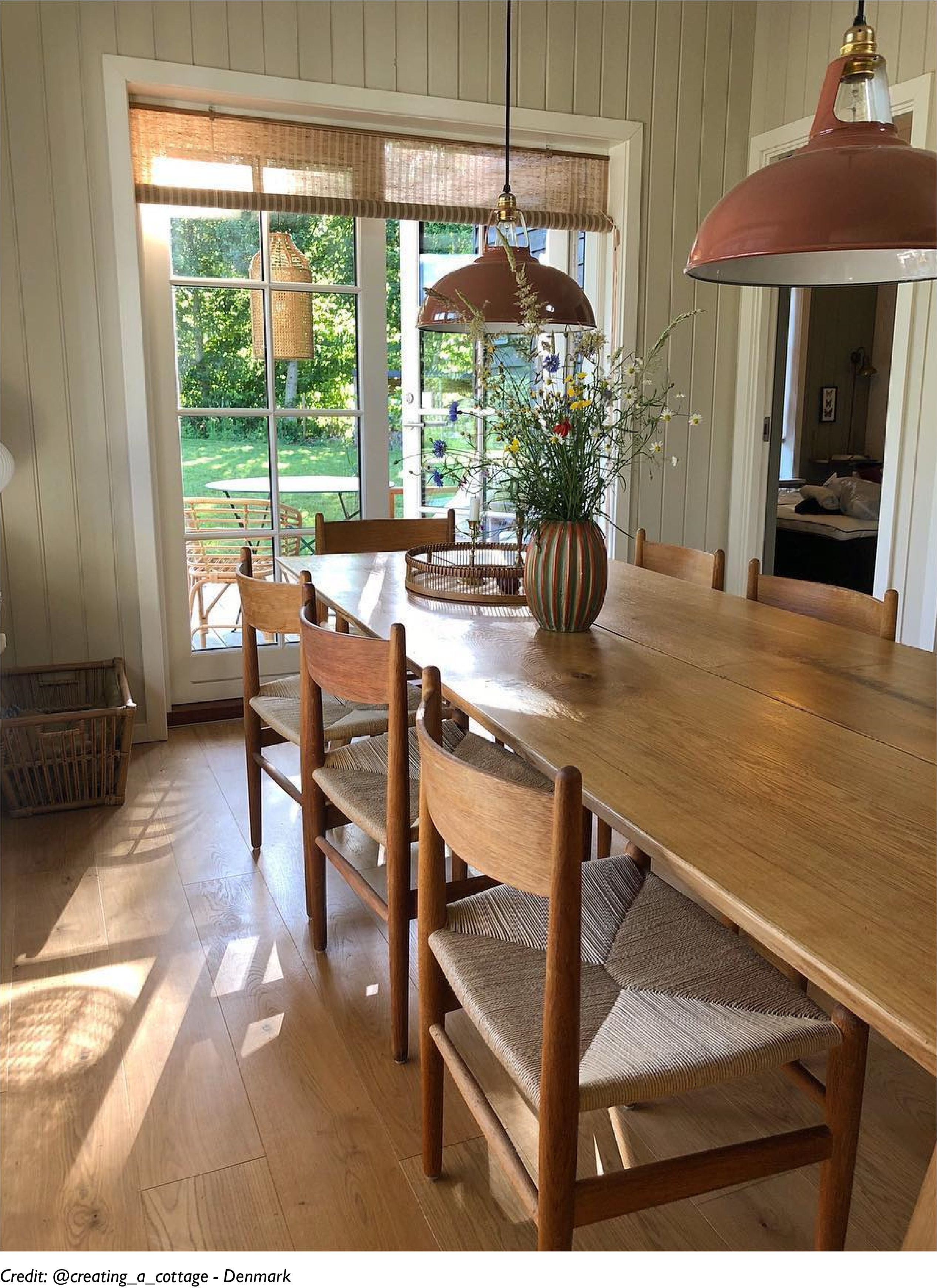 Two Large Terracotta lampshades hang over a long wooden dining table in a modern interior