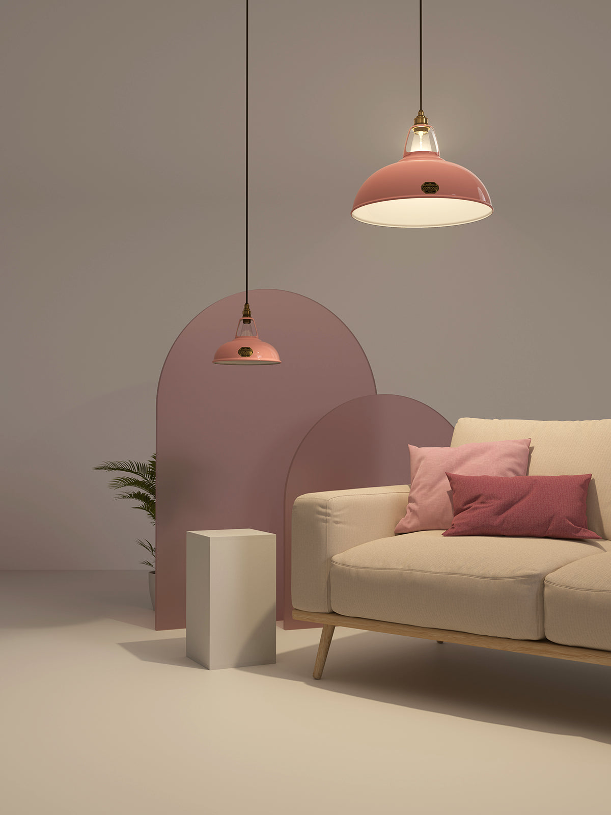 An Original and a Large Pink lampshade hang over a cream sofa, with pink glass panels in the background