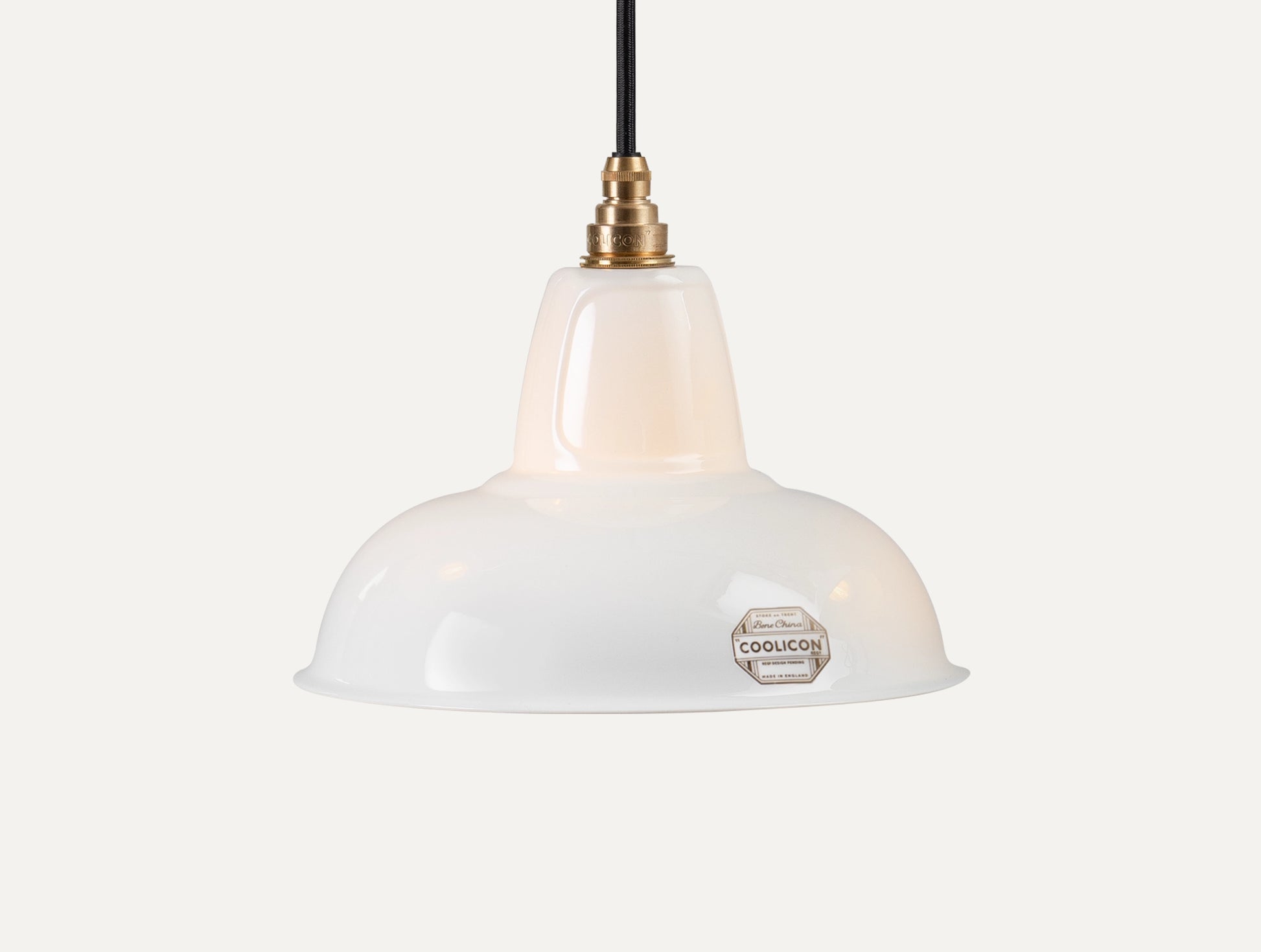 A Fine Bone China Silhouette Coolicon shade with a Signature Brass pendant set hangs over a light grey background