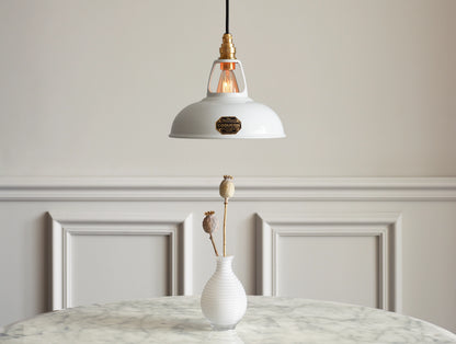 A Coolicon Original White lampshade hanging over a marble table. Below the shade is a white tall vase with a couple of dried poppies in it