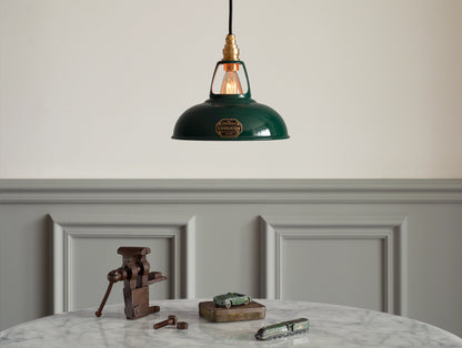 A Coolicon Original Green lampshade hanging over a marble table. A rusty vise, a green toy car and a green toy train