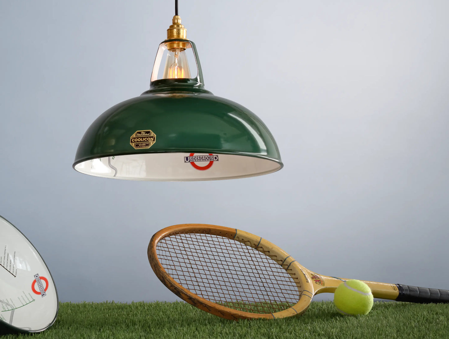 A Large District Line Green shade above a patch of grass. Below it is a wooden tennis racket and a tennis ball